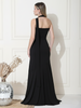 Woman wearing a black halter neck gown against a white wall.