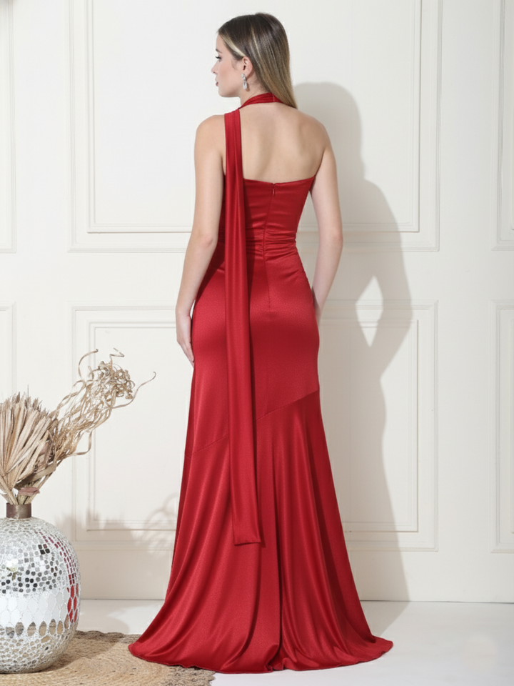Woman wearing a red evening gown against a white wall.